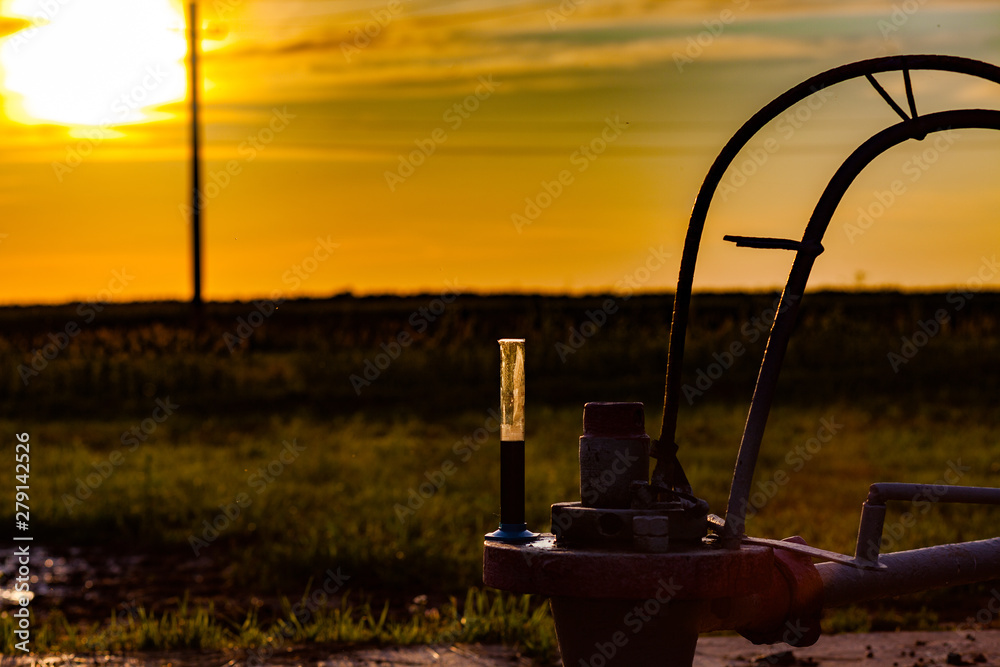The flask of oil is at the well of the oil pump. Oil quality control. Oil production in Russia. Sunset.