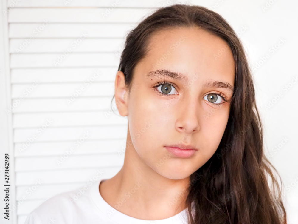 Portrait of a beautiful young caucasian tanned girl on a white background closeup. Brown long health hair. Calm face, beauty concept. Portrait of a beautiful young caucasian tanned girl on a white background closeup. Brown long health hair. Calm face, beauty concept.