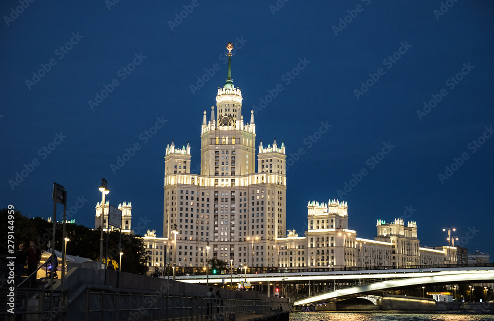 Obraz premium City landscape, view of the Moscow river with pleasure boats, Stalin skyscraper in the night
