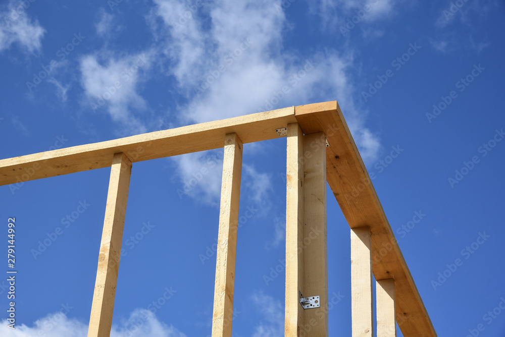 Wood frame residential building under construction.Building construction, wood framing structure at new property development site.new home currently under construction against blue sky.mortgage, loan. Wood frame residential building under construction.Building construction, wood framing structure at new property development site.new home currently under construction against blue sky.mortgage, loan.