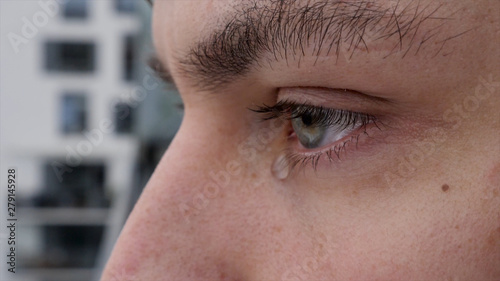 close up of a young man crying and tear falling 