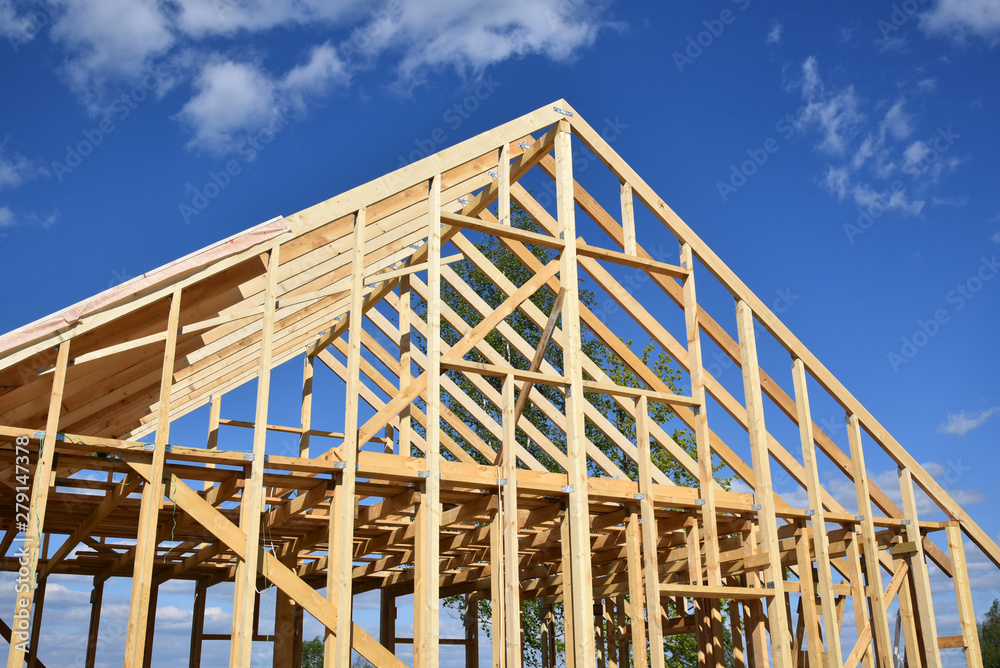 Wood frame residential building under construction.Building construction, wood framing structure at new property development site.new home currently under construction against blue sky.mortgage, loan. Wood frame residential building under construction.Building construction, wood framing structure at new property development site.new home currently under construction against blue sky.mortgage, loan.