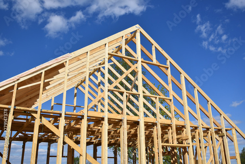 Wood frame residential building under construction.Building construction, wood framing structure at new property development site.new home currently under construction against blue sky.mortgage, loan.