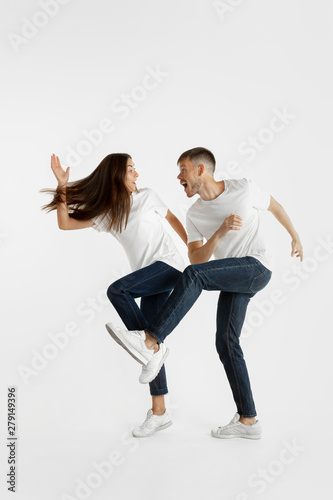 Beautiful young couple's portrait isolated on white studio background. Facial expression, human emotions, advertising concept. Copyspace. Woman and man jumping, dancing or running together.