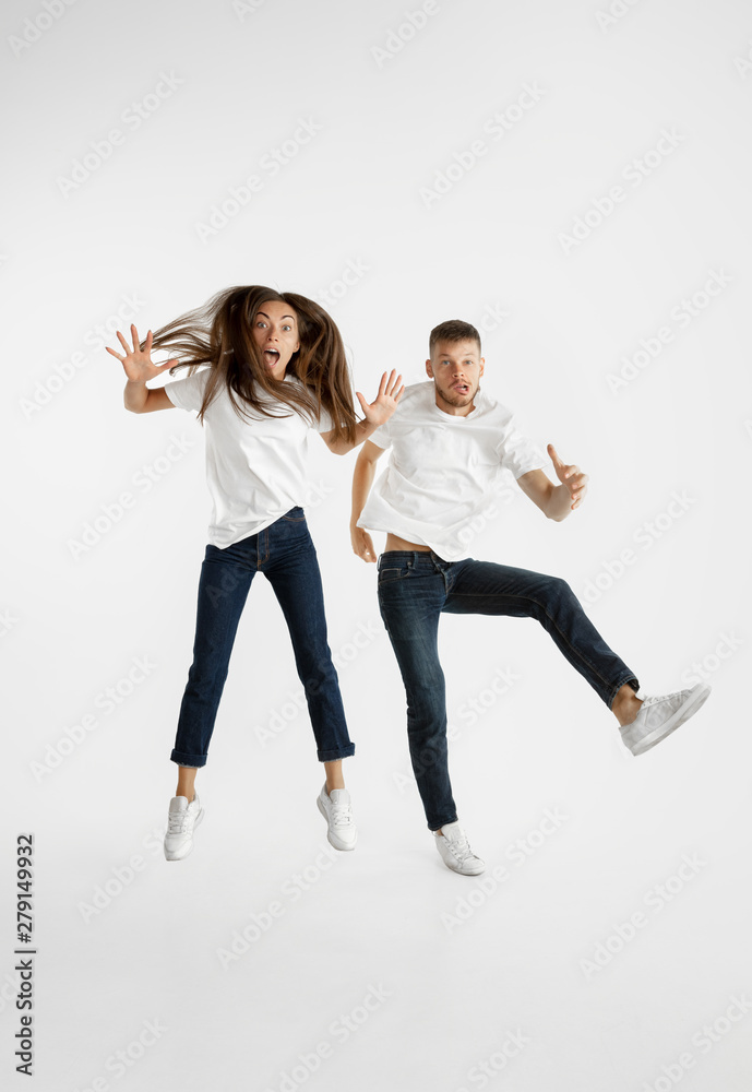 Beautiful young couple's portrait isolated on white studio background. Facial expression, human emotions, advertising concept. Copyspace. Woman and man jumping, dancing or running together.