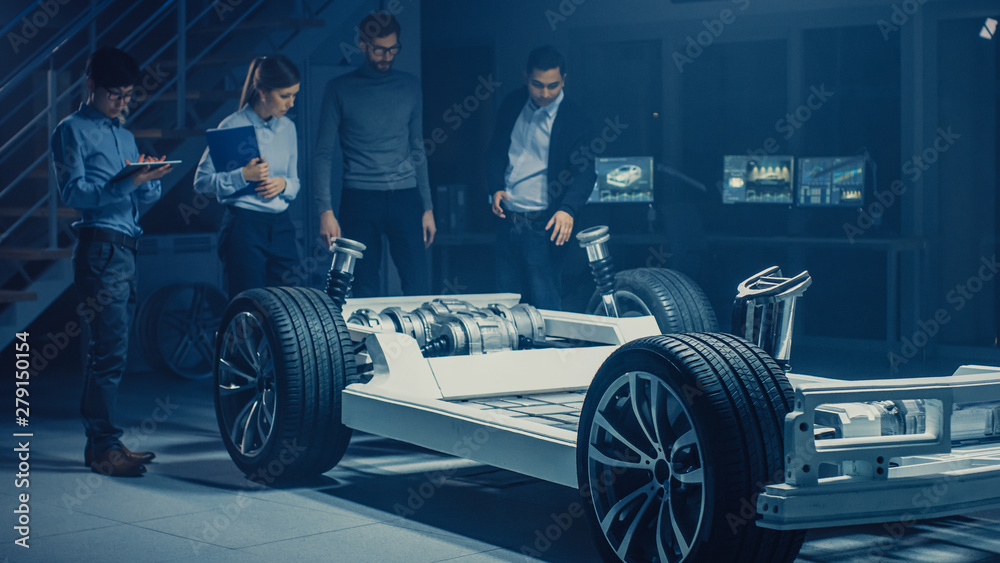 Team of Automotive Engineers Designing Electric Car Platform Chassis Prototype, Taking Measures, Working with 3D CAD Software, Checking Quality Control. Vehicle Frame with Wheels, Engine and Battery. Team of Automotive Engineers Designing Electric Car Platform Chassis Prototype, Taking Measures, Working with 3D CAD Software, Checking Quality Control. Vehicle Frame with Wheels, Engine and Battery.