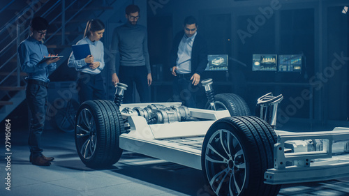 Team of Automotive Engineers Designing Electric Car Platform Chassis Prototype, Taking Measures, Working with 3D CAD Software, Checking Quality Control. Vehicle Frame with Wheels, Engine and Battery.  © Gorodenkoff