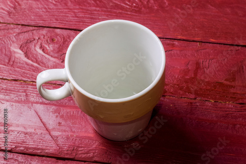 Empty cup on claret color wooden background.