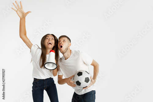 Portrait of beautiful young couple football or soccer fans on white studio background. Facial expression, human emotions, advertising, sport concept. Woman and man jumping, screaming, having fun. photo