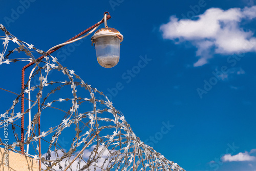 Barbed wire on a fence with light lamps. Barbwire on dark blue sky background. photo