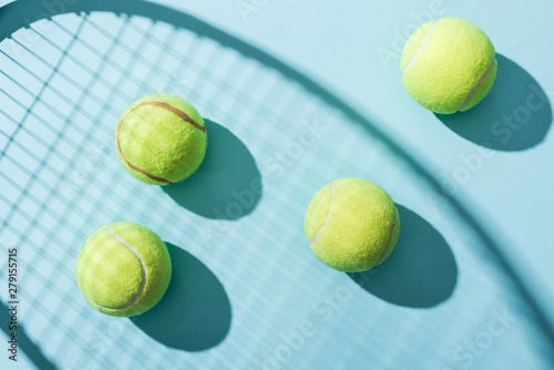 top view of tennis balls near shadow of tennis racket on blue © LIGHTFIELD STUDIOS