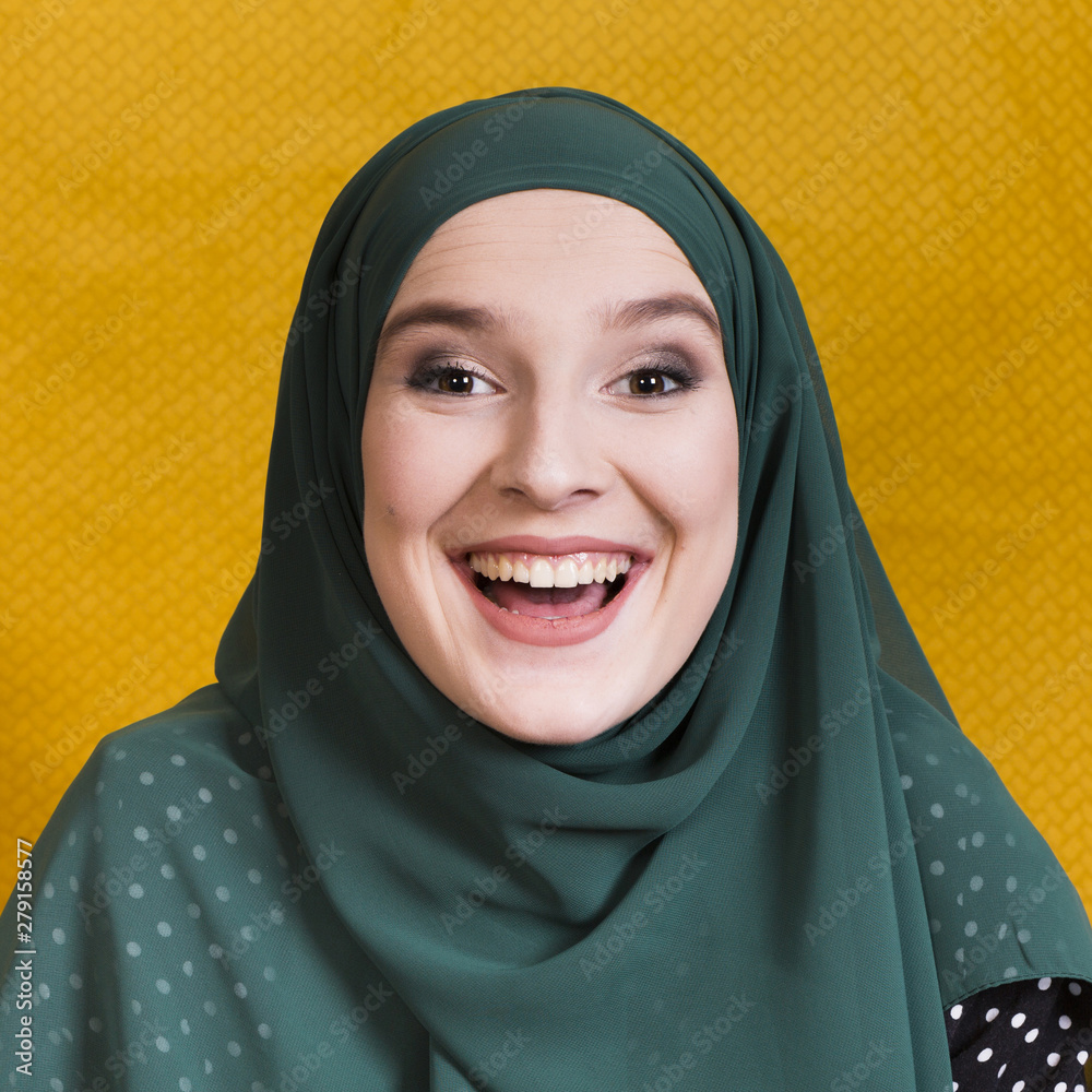 Front view of cheerful arabian woman on yellow backdrop Front view of cheerful arabian woman on yellow backdrop