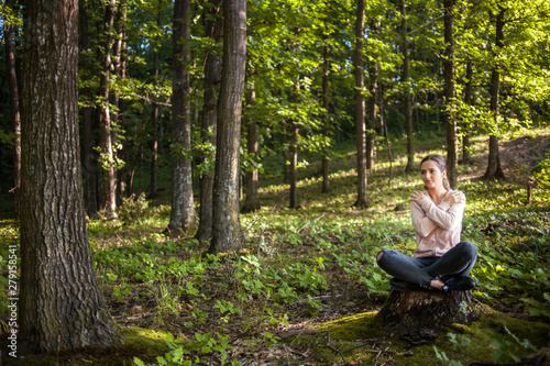 Beautiful woman meditating in the forest on a sunny morning