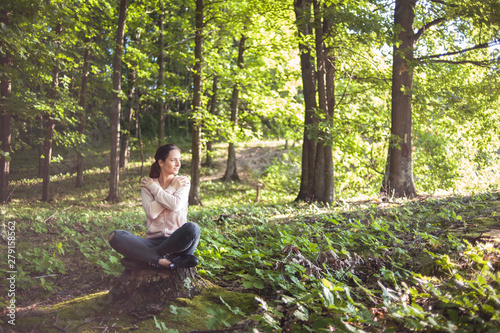 Beautiful woman meditating in the forest on a sunny morning