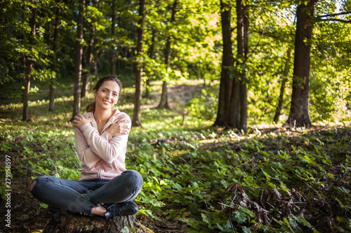 Beautiful woman meditating in the forest on a sunny morning