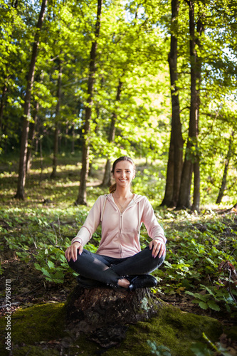 Beautiful woman meditating in the forest on a sunny morning