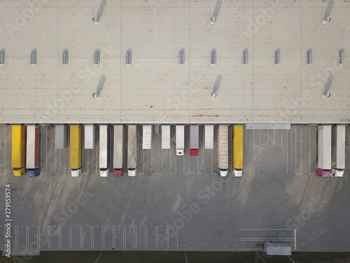 Aerial view of goods warehouse. Logistics center in industrial city zone from above. Aerial view of trucks loading at logistic center. View from drone.