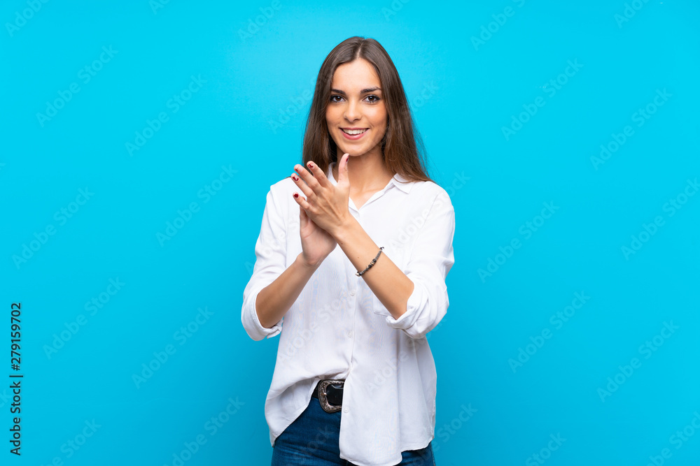 Young woman over isolated blue background applauding after presentation in a conference Young woman over isolated blue background applauding after presentation in a conference