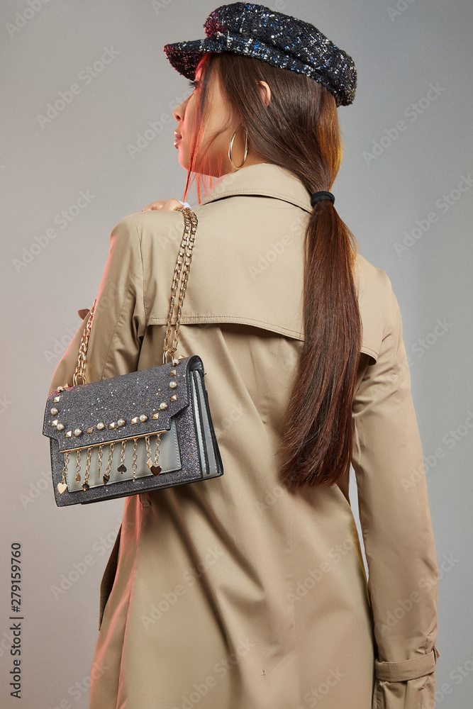 Three quarter back shot of lady, wearing trench coat and silver 