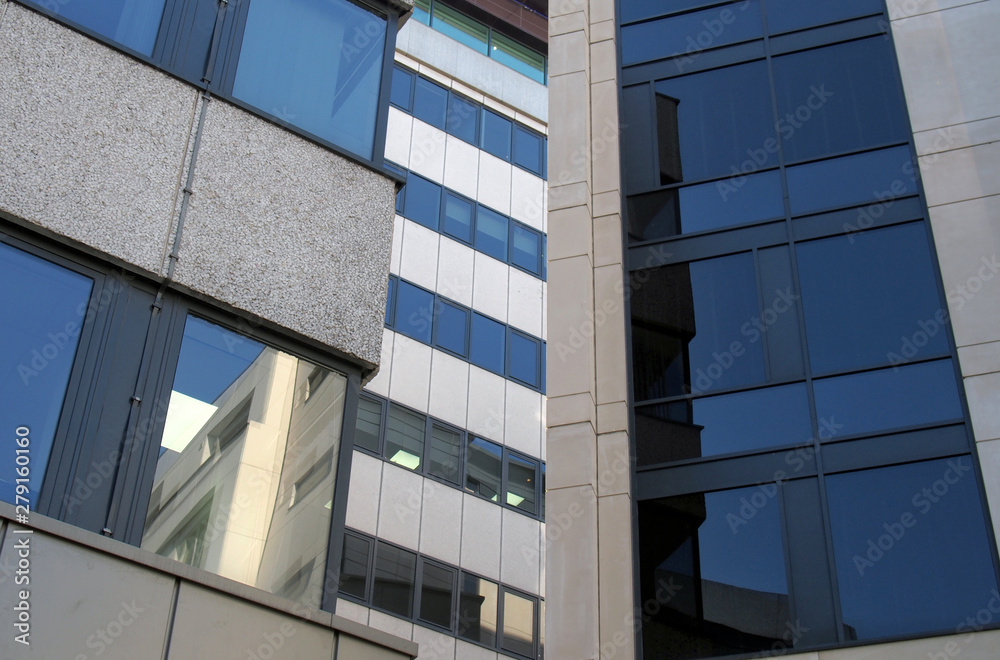 Obraz premium windows and reflections in the windows of a group of large modern office buildings in a city business district
