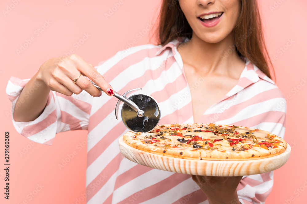 Young woman holding a pizza over isolated pink wall