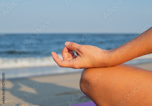 Close-up female hand in gyan mudra and lotus position. Woman practicing yoga and meditating.