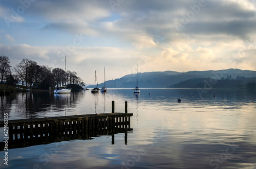 A still quiet peaceful evening at Lake Windermere showing a pier boats and a calm lake. © Garry Basnett