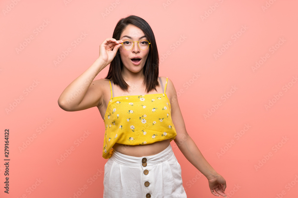 Young Mexican woman over isolated wall with glasses and surprised Young Mexican woman over isolated wall with glasses and surprised