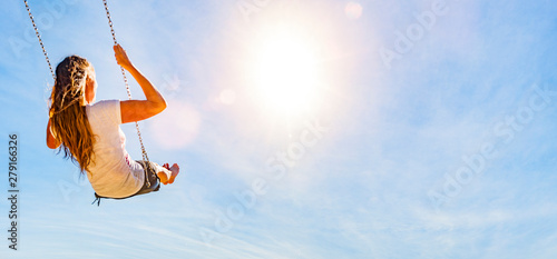 Frau auf einer Schaukel mit blauem Himmel im Gegenlicht