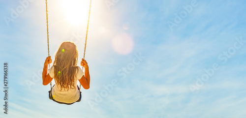 Frau auf einer Schaukel mit blauem Himmel im Gegenlicht