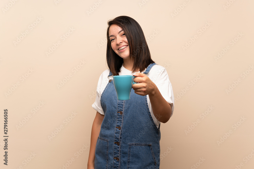 Young Mexican woman over isolated background holding hot cup of coffee Young Mexican woman over isolated background holding hot cup of coffee