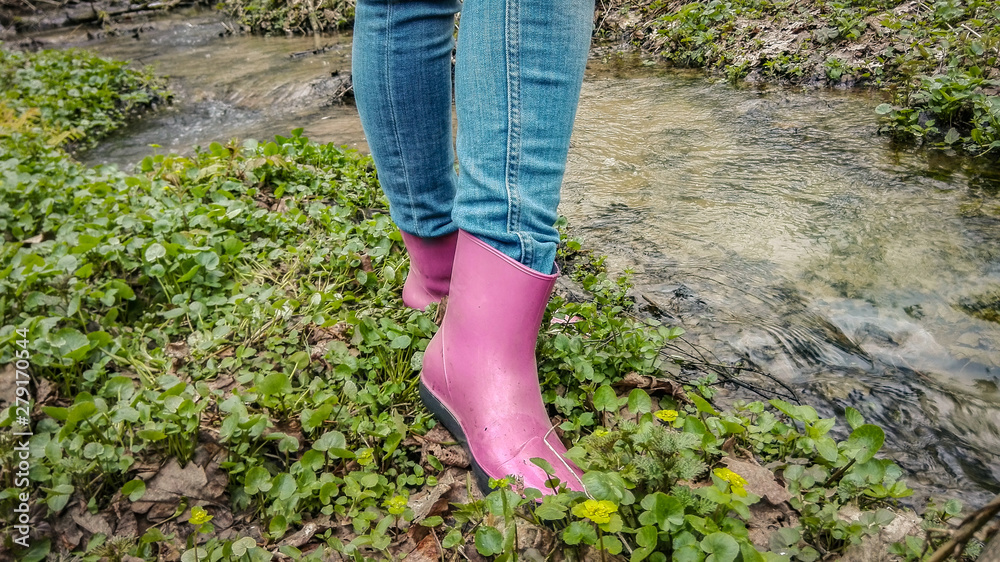 Woman in pink rubber boots on the nature on the grass