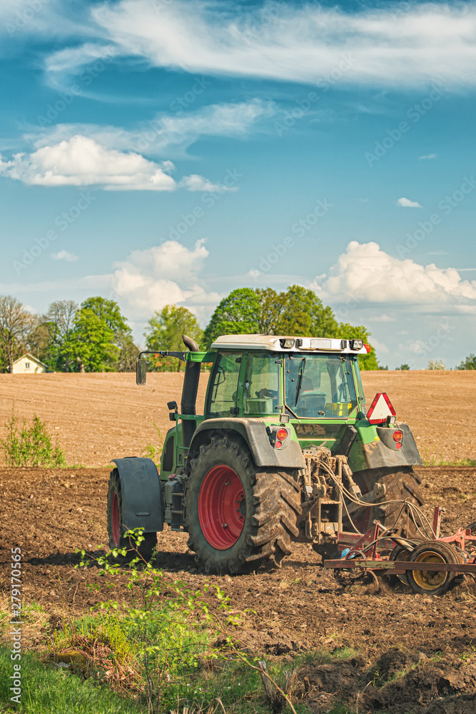 Naklejka premium Tractor working on the farm, a modern agricultural transport, a farmer working in the field, fertile land, tractor on a sunset background, cultivation of land, agricultural machine