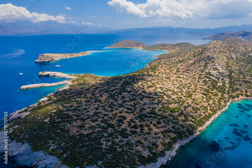 Aerial view of a clear, deep blue ocean and dry, yellow summer coastline (Kolokitha Island, Greece) photo