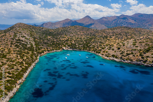 Aerial drone view of a warm, blue, clear ocean with dry coastline and boats (Kolokitha Island, Elounda, Crete) photo