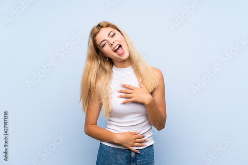 Teenager girl over isolated blue background with phone in victory position