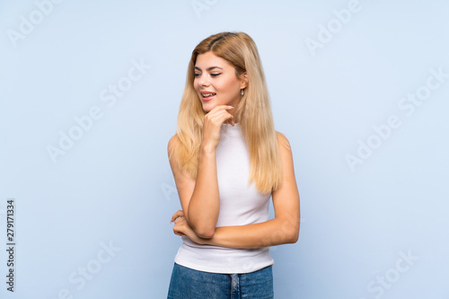 Teenager girl over isolated blue background with glasses and surprised © luismolinero