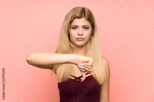 Teenager girl over isolated pink background showing thumb down sign