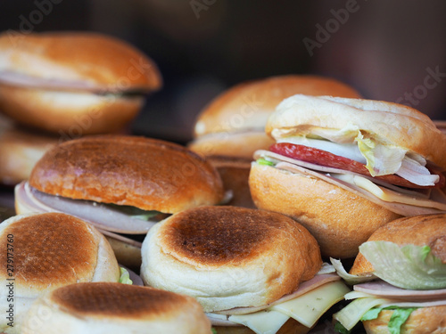 Pile of burgers, homemade sandwiches with greens, cheese and sausage photo