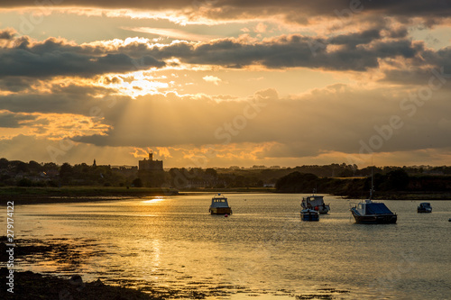 View up the River Coquet from Amble towards Warkworth on the coast of Northumberland, England, UK. At sunset with orange coloued sky and clouds. photo