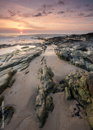 Sunrise and dawn light over the rocks on Cresswell Beach on the coast of Northumberland, England, UK. photo