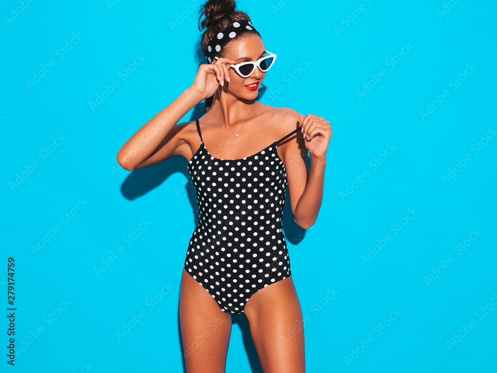 Young beautiful sexy hipster woman in sunglasses.Trendy girl in summer peas swimwear bathing suit. Positive female going crazy.Funny model isolated on blue