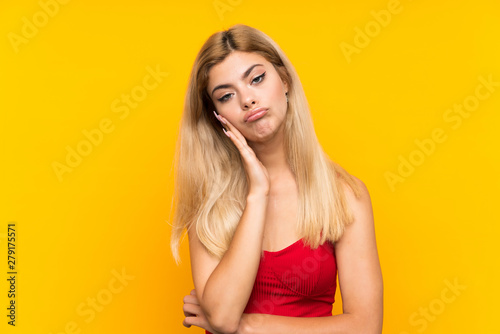 Teenager girl over isolated yellow background unhappy and frustrated