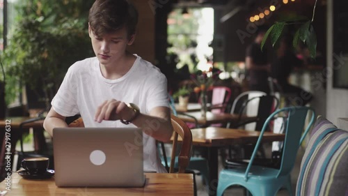 Young man surfing website and chatting, freelancer and blogger working as a graphic designer indoor, modern working place sitting in cafe. Open laptop in restaurant.