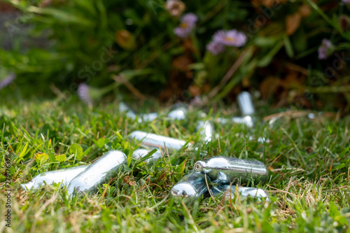 Quadro em tela Discarded laughing gas canisters / cream chargers in the grass: metal vials containing nitrous oxide gas, used for whipping cream, but also as a legal high