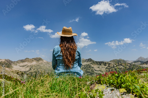 Frau mit Stohhut sitzt zwischen Alpenrosen
