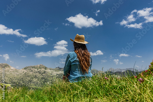 Frau mit Stohhut sitzt zwischen Alpenrosen