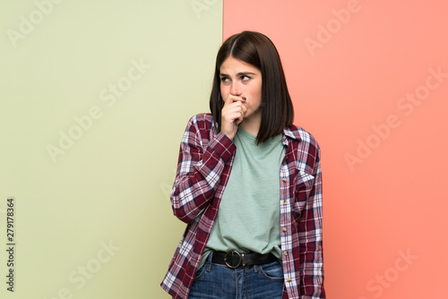Young woman over isolated colorful wall having doubts © luismolinero