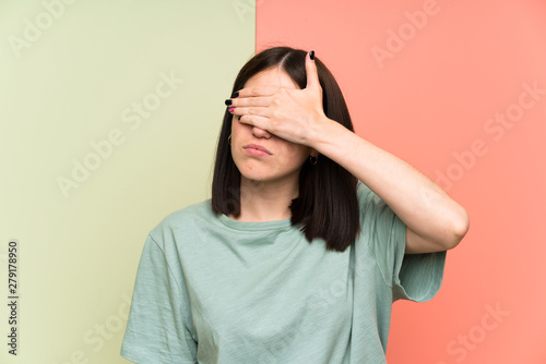 Young woman over isolated colorful wall covering eyes by hands © luismolinero