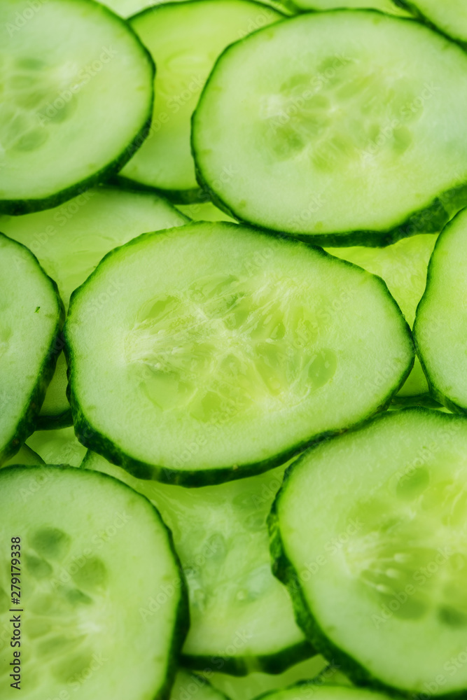 Slices of green fresh cucumber backlit as a textural background Slices of green fresh cucumber backlit as a textural background